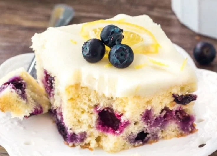Lemon blueberry cake with fresh blueberries and lemon zest on a white plate