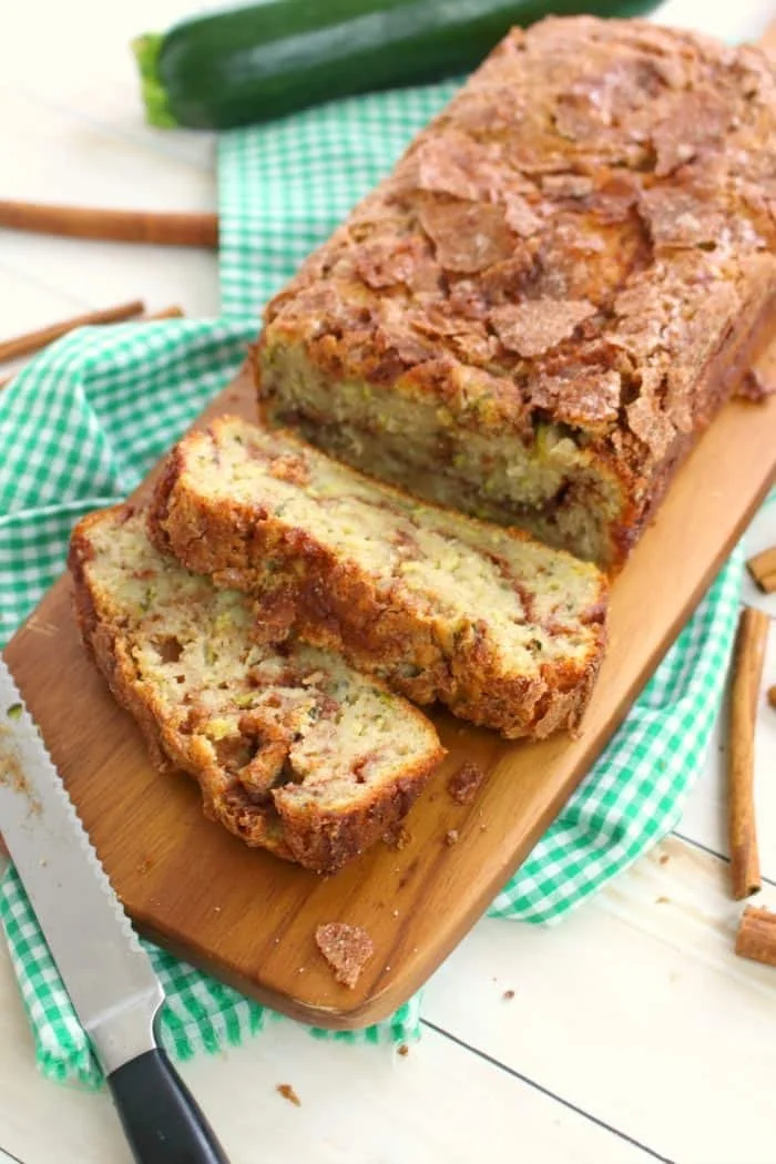 Moist and delicious cinnamon swirl zucchini bread slice on a wooden platter