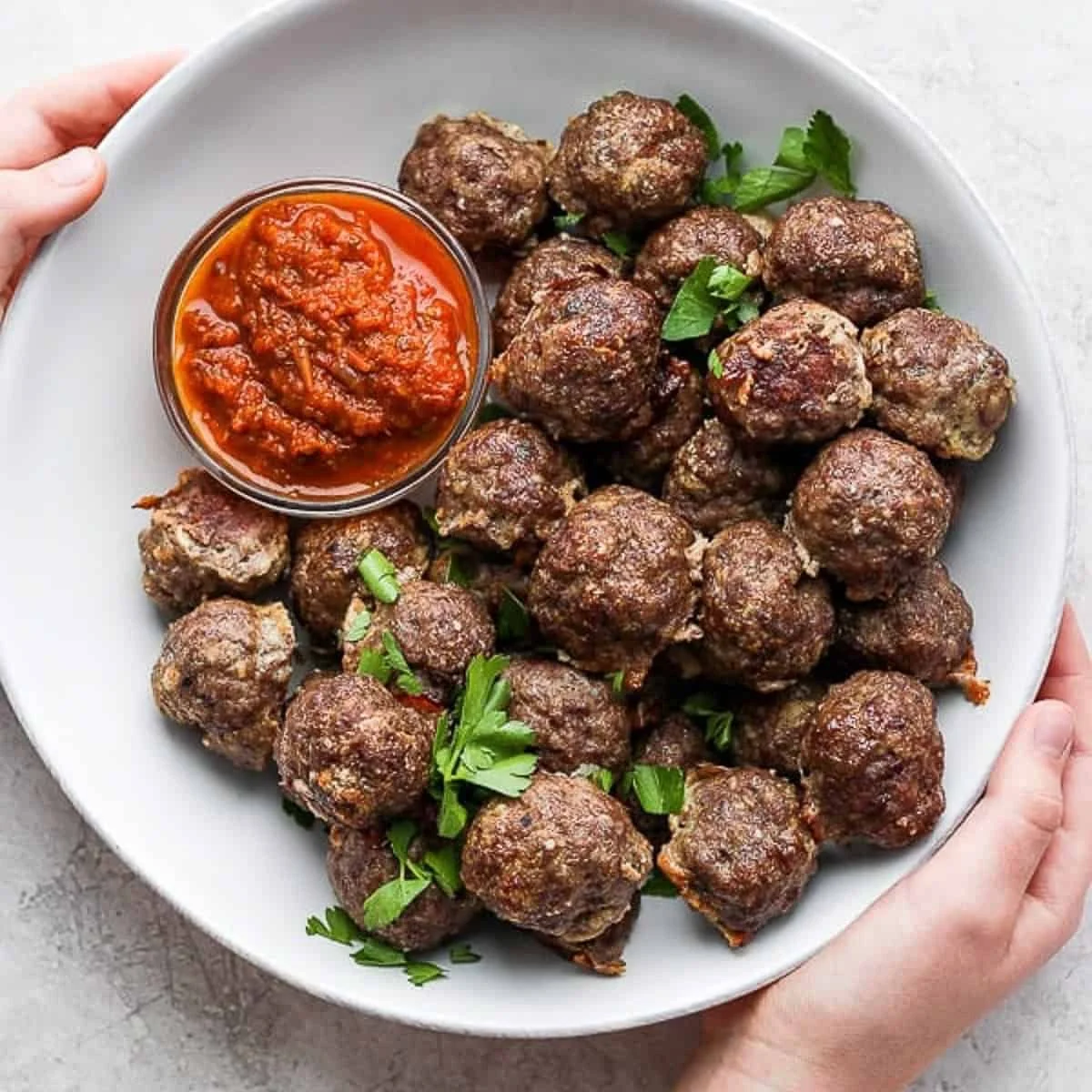 Oven baked meatballs on a platter garnished with parsley