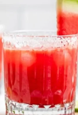 Skinny watermelon margarita served in a glass with lime garnish.